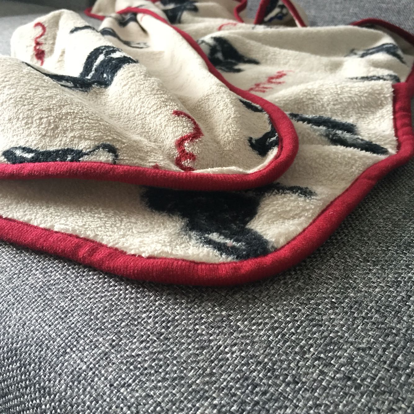 Beige fleece pet blanket with red piping edge and black dog graphic