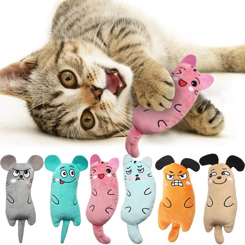 Pink cat plush toy with embroidered face, held by grey tabby cat.