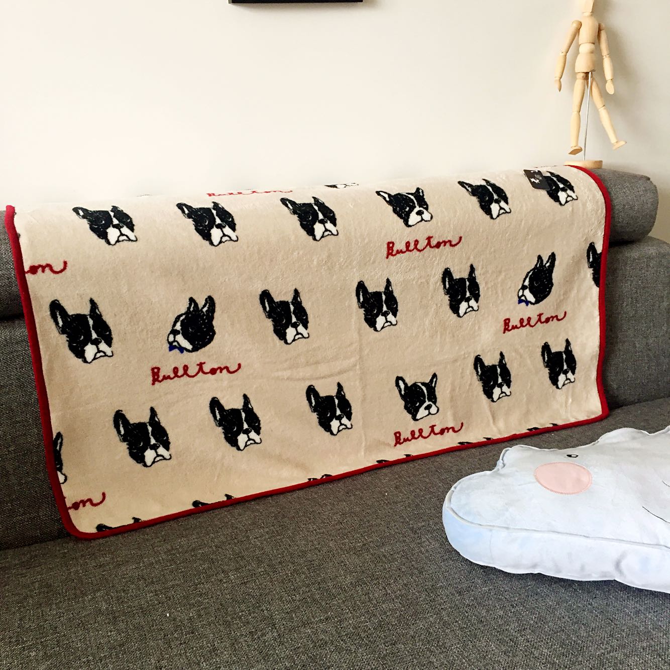 Beige dog-print blanket with repeating black dog faces and red trim