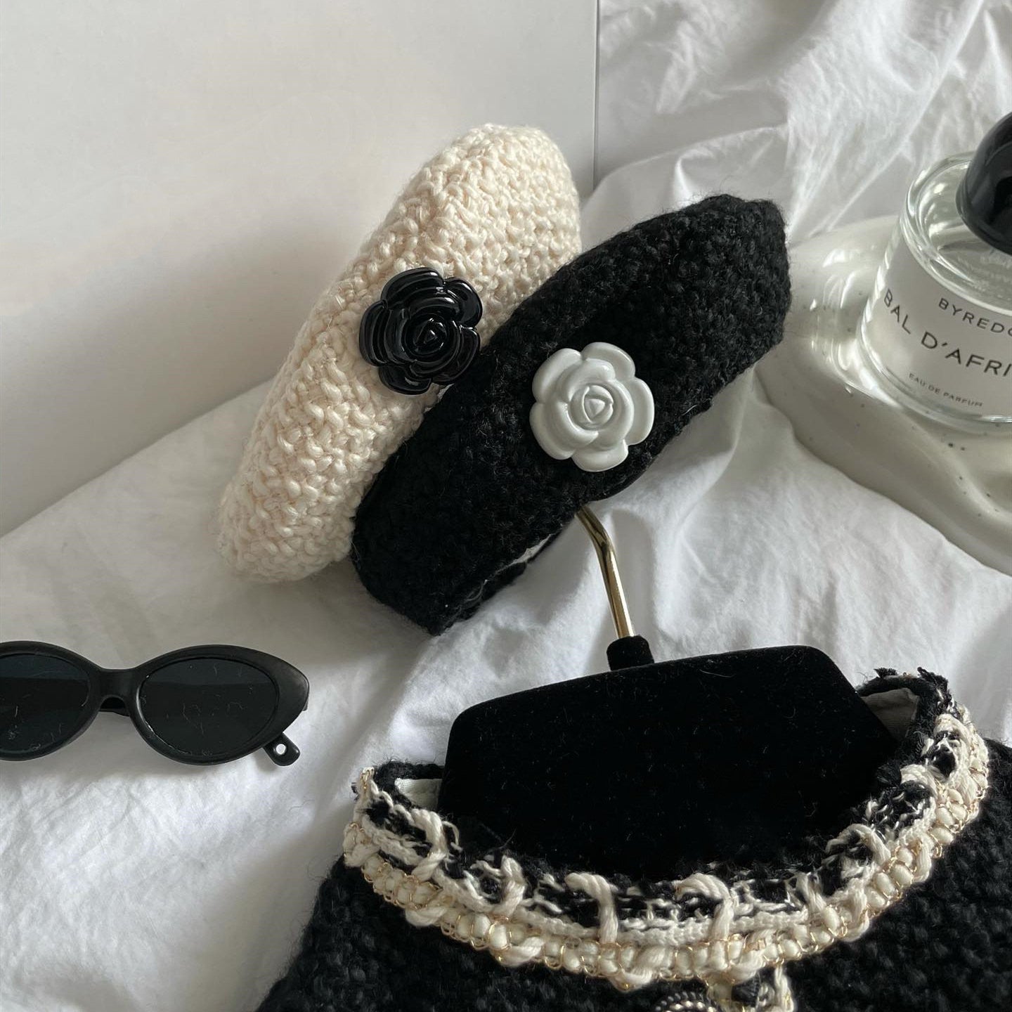 Two knit pet beanies: black and beige, each with flower embellishment
