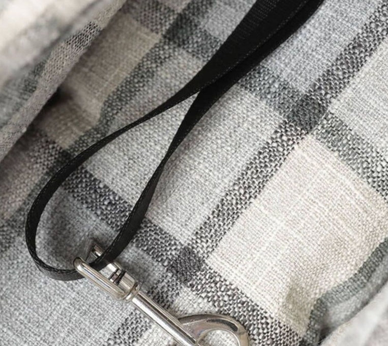 Plaid pet bag close-up: black strap with metal clasp and reinforced stitching