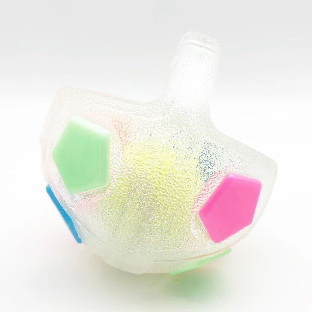 Close-up white football-shaped dog toy with green, pink and blue hex panels